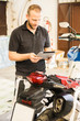 © Westend61 - Man using tablet next to motorcycle in workshop