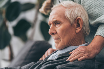 Wall Mural - cropped view of retired wife embrace sad senior husband at home