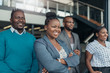 © JonoErasmus - Portrait of a confident black businesswoman smiling crossing her arms with all african team in the background