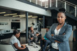 © JonoErasmus - Portrait of a confident black businesswoman with her arms crossed and all african team in the background