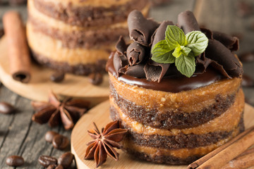 Wall Mural - Dark chocolate cakes on black slattern board with mint, cinnamon, coffee beans on a wooden  background. Tasty dessert food concept.