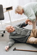 © LIGHTFIELD STUDIOS - old woman helping to stand up husband who falled down on floor with walking stick