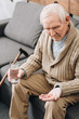 © LIGHTFIELD STUDIOS - senior man holding pills and glass of water and looking at hand