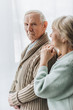 © LIGHTFIELD STUDIOS - senior wife looking at retired husband and standing at home