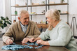 © LIGHTFIELD STUDIOS - happy senior couple playing with puzzles at home