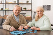 © LIGHTFIELD STUDIOS - cheerful senior couple smiling and playing puzzles at home