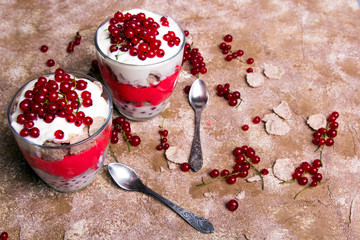 Wall Mural - Healthy dessert with organic red currants, fresh yogurt and corn flakes. Dietary breakfast on a brown background