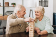 smiling pensioners playing jenga game on table