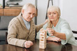 © LIGHTFIELD STUDIOS - retired couple playing jenga game on table at home
