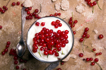 Wall Mural - Healthy dessert with organic red currants, fresh yogurt and corn flakes. Dietary breakfast on a brown background