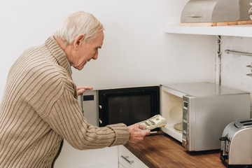 Wall Mural - senior man with dementia disease putting dollars in microwave oven