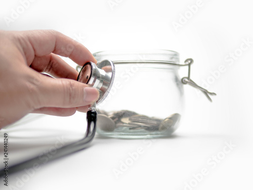 Fotografía Listening to Saving money concept, coins in Glass Jar and stethoscope
