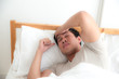 © Asada - Asian man lying on the bed and hand on forehead. Illness,stress,headache caused by overworking or hard work