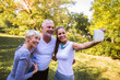 © Mediteraneo - Senior man and woman and young female instructor workout on fresh air make selfie with smart phone. Outdoor activities, healthy lifestyle, strong bodies, fit figures.