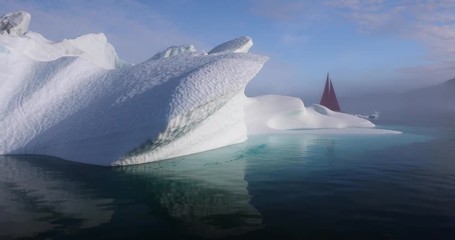 Wall Mural - little red sailboat cruising among floating icebergs in disko bay glacier during midnight sun season
