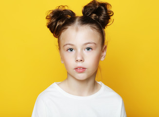 Wall Mural - smiling little girl in casual clothes over yellow background