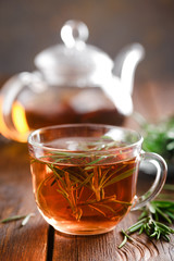 Poster - Rosemary tea in glass tea cup on rustic wooden table closeup. Herbal vitamin tea.