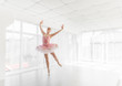 Elegant female ballet dancer in pink tutu practicing and smiling