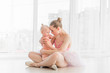 Young mother hugging little smiling daughter in ballet studio