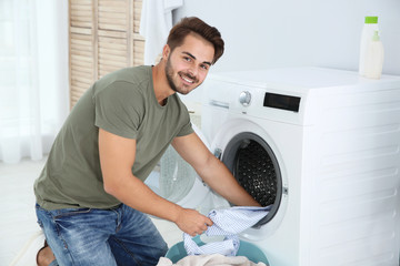 Wall Mural - Young man using washing machine at home. Laundry day