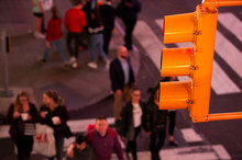 (focus On The Traffic Light) Close-up View Of A Traffic Light And Blurred People In The Background Crossing The Street In Times Square, New York City, United States.