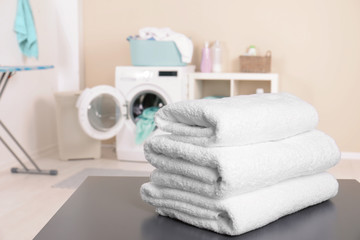 Sticker - Stack of clean towels on table in laundry room. Space for text