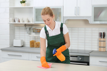 Poster - Female janitor cleaning table with rag in kitchen