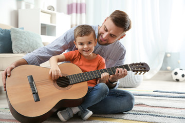 Canvas Print - Father teaching his little son to play guitar at home