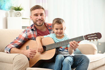 Canvas Print - Father teaching his little son to play guitar at home