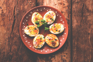 Fried hot boiled egg masala is a popular healthy breakfast or starter menu from India. With onion, coriander, black pepper, tomato and salt sprinkled over half of eggs