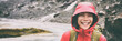 Active outdoors people lifestyle - happy hiker Asian woman laughing in the rain on mountain hike - Outdoors adventure trek activity, wearing waterproof raincoat sportswear clothes. Banner panorama.