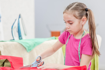 Little girl cuts dress detail with scissors. Space for text