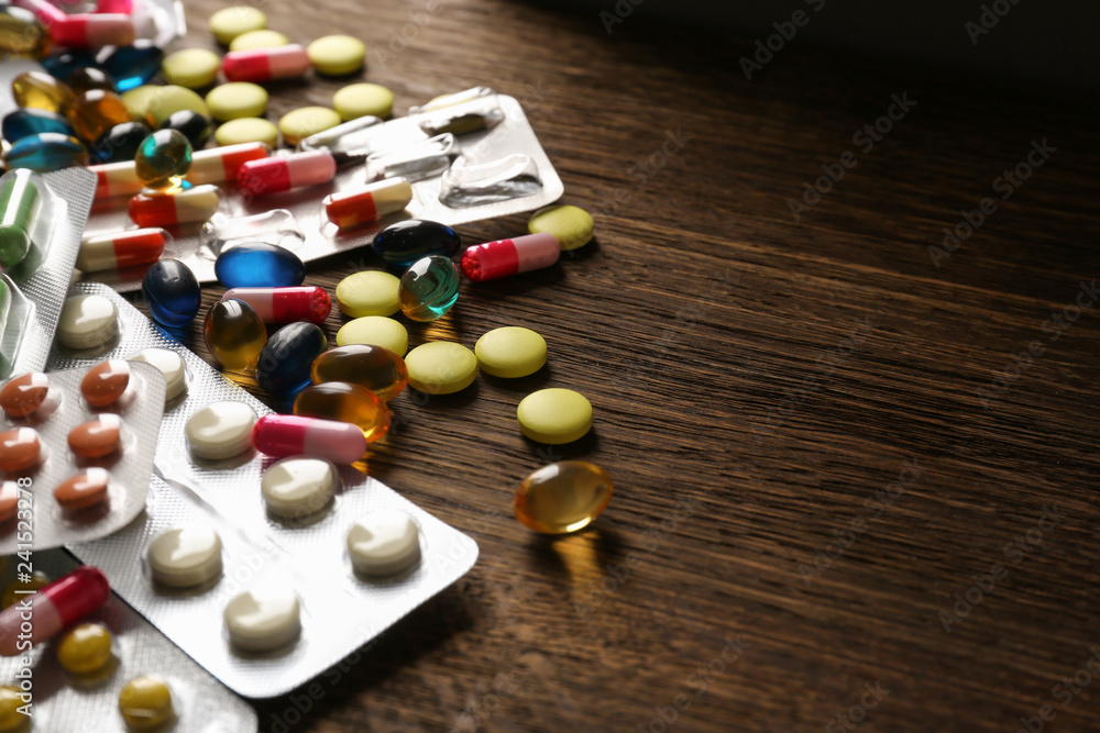 Different pills on wooden background