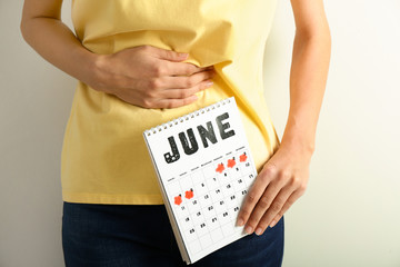 Wall Mural - Woman with menstrual calendar on light background