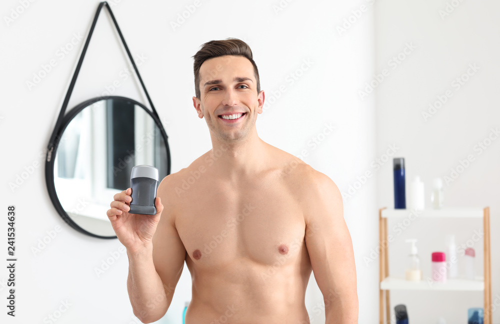 Handsome young man with deodorant in bathroom