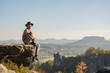 © serejkakovalev - Young bearded male traveler in hat stand on the cliff in sunny day