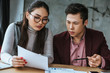 © LIGHTFIELD STUDIOS - focused young asian business colleagues looking at papers in office