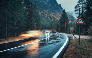 Wall Mural - blurred cars in motion on the road in autumn forest in rain. perfect asphalt mountain road in overca