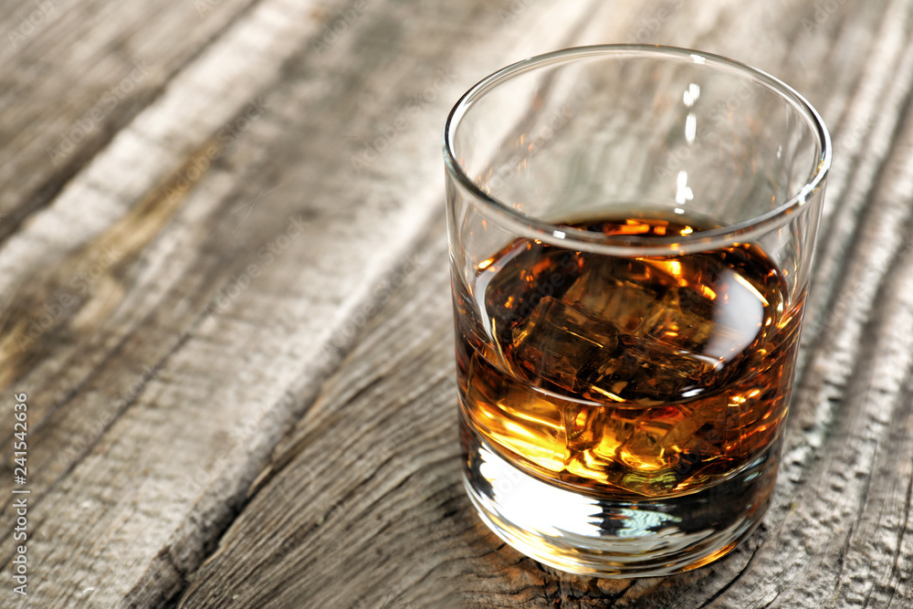 Glass of whiskey on wooden table