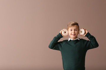 Wall Mural - Cute little boy with donuts on color background