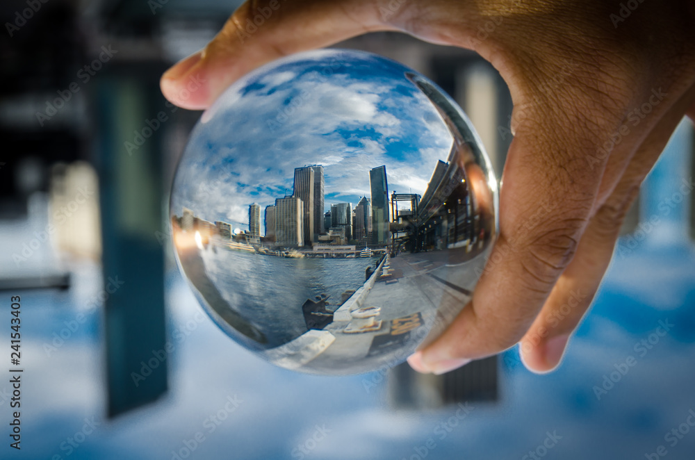Cityscape photography in a clear glass crystal ball with dramatic clouds sky. - obrazy, fototapety, plakaty 