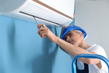 Wall Mural - Male technician repairing air conditioner indoors