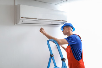 Wall Mural - Male technician repairing air conditioner indoors