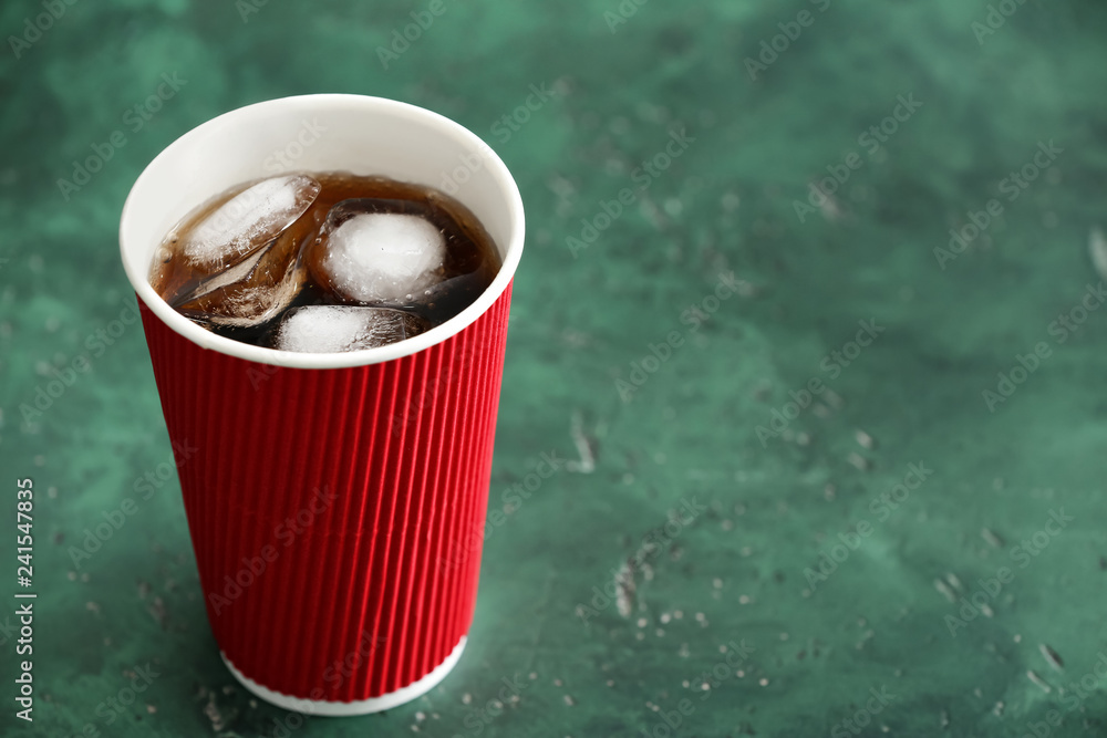 Paper cup of tasty soda on color table
