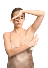 Poster - Beautiful young woman with deodorant feeling smell of sweat on white background. Concept of using deodorant