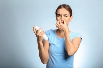 Poster - Beautiful young woman with deodorant feeling smell of sweat on light background. Concept of using deodorant