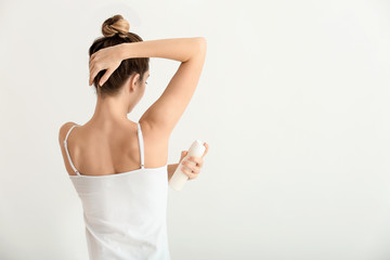 Sticker - Beautiful young woman with deodorant on light background