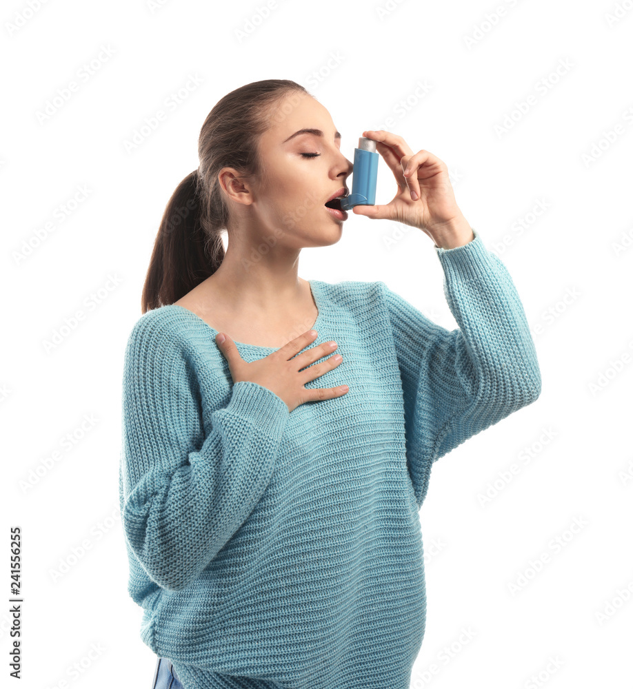 Young woman with inhaler having asthma attack on white background