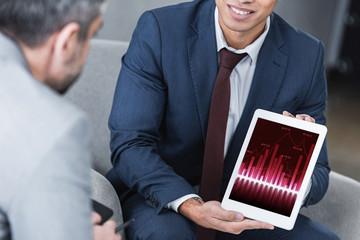 Wall Mural - cropped shot of smiling young businessman showing digital tablet with business graphs to colleague