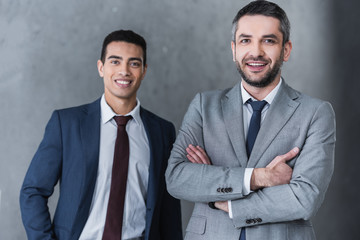 Wall Mural - professional confident businessmen standing together and smiling at camera on grey